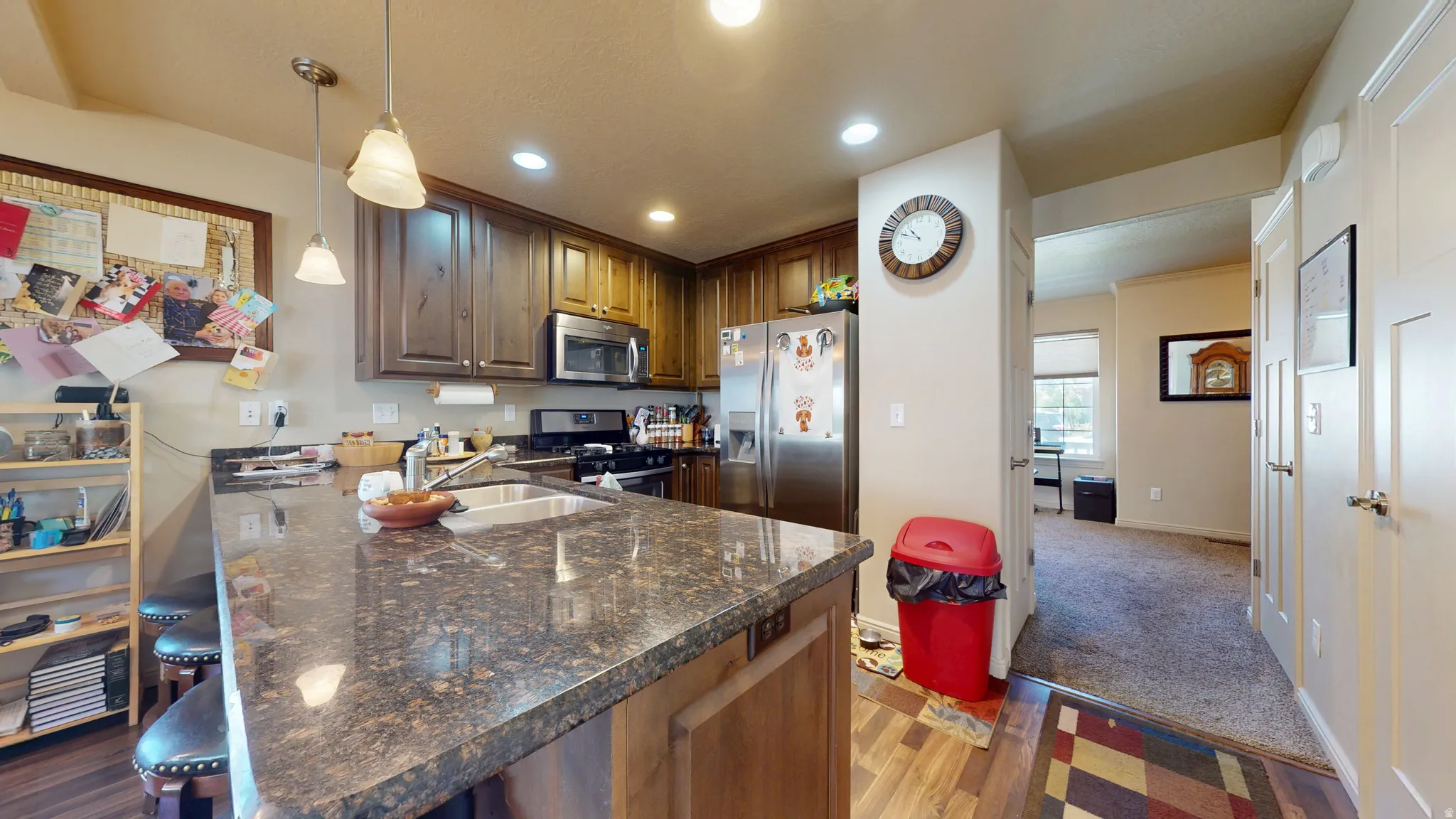 Kitchen featuring a breakfast bar with stone-finish countertop, wood-finish cabinetry, stainless steel appliances, and recessed lighting