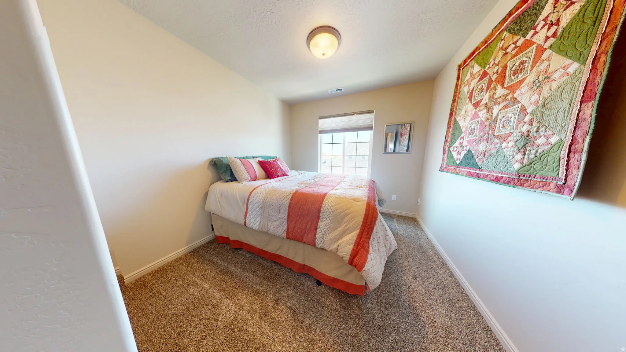 Carpeted bedroom featuring neutral walls and a ceiling-mounted light fixture