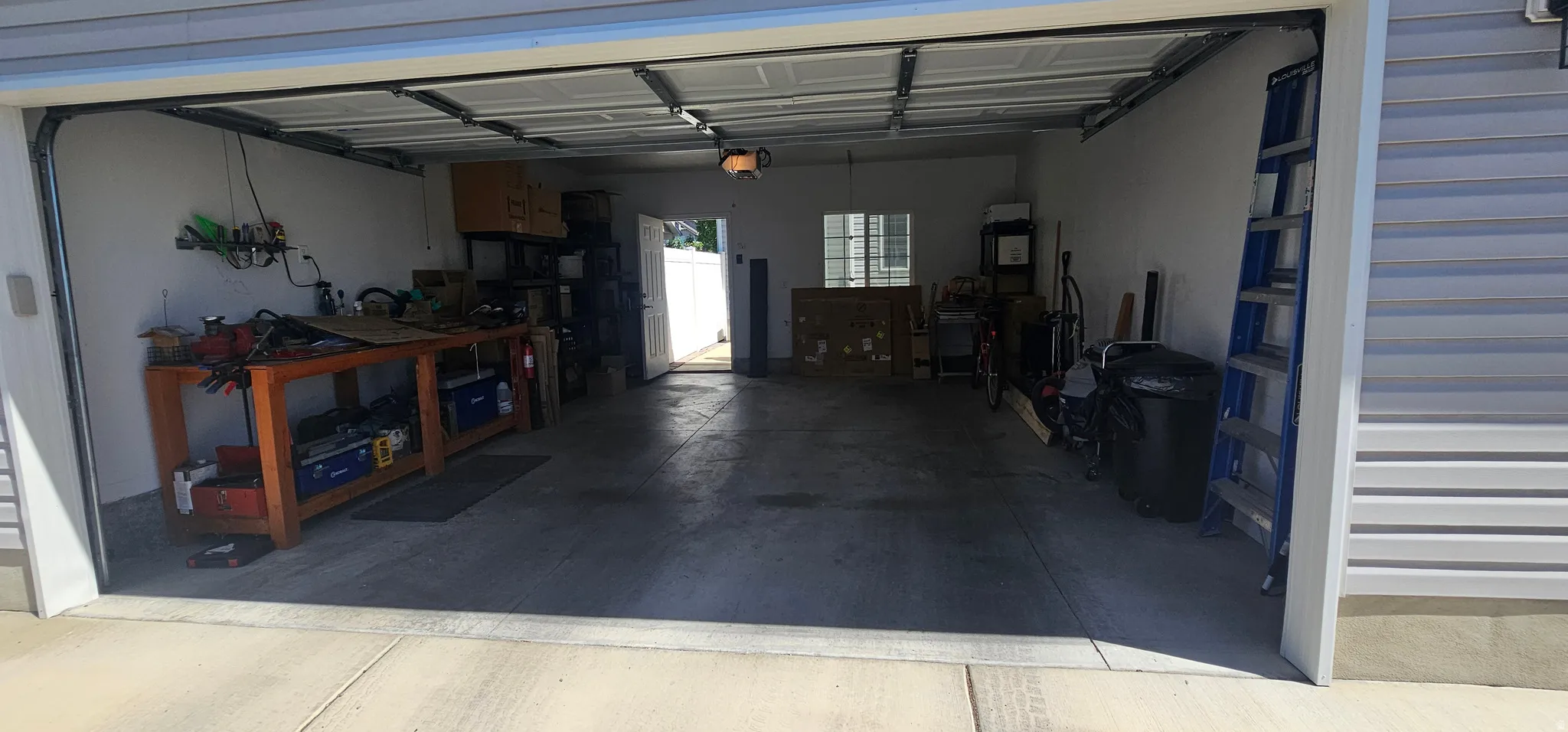 Two-car garage featuring a concrete floor, overhead lighting, and white walls