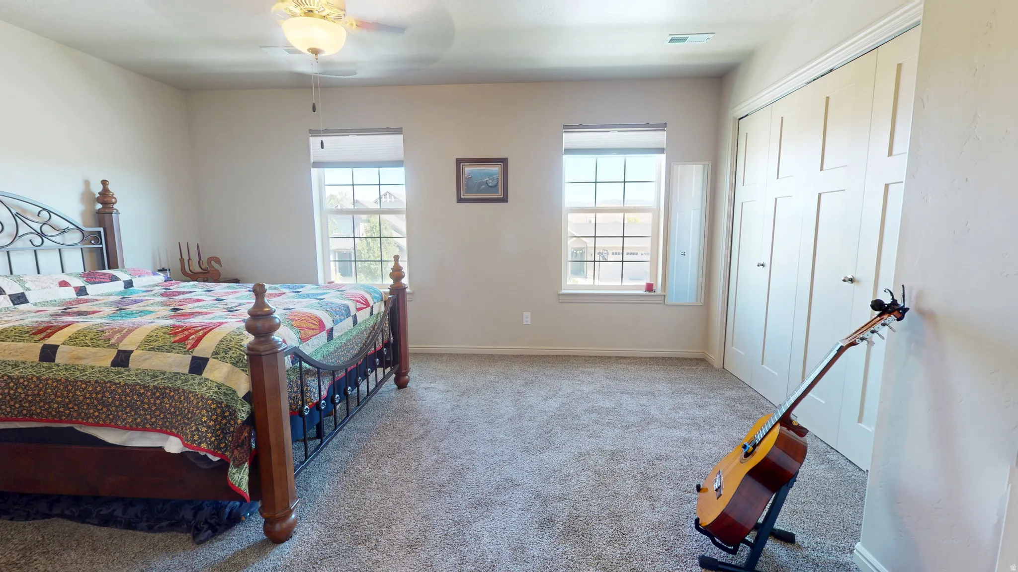 Bedroom featuring light neutral wall paint, two windows with gridded panes, a multi-panel closet with dual doors, and light gray carpeted flooring