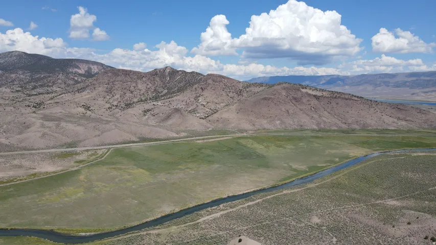 Expansive land parcel featuring a winding river, verdant fields, and a mountainous backdrop