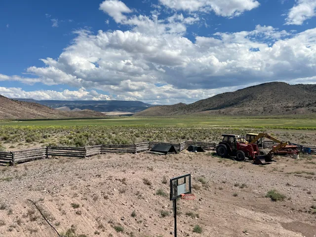 Expansive land parcel featuring natural terrain, a split-rail fence, and distant mountain scenery