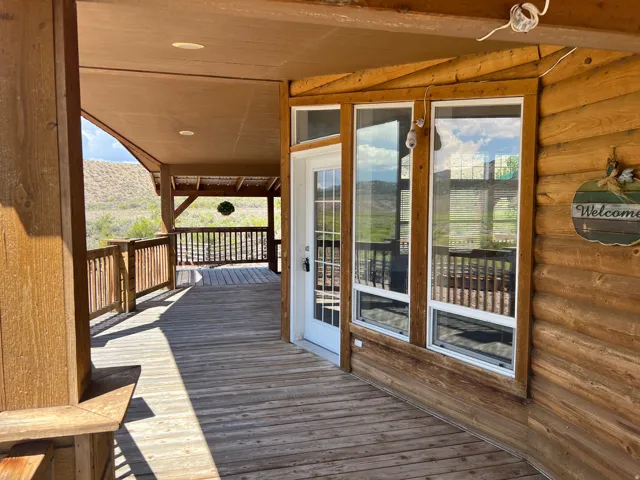 Expansive covered porch featuring wood-finish decking, log-style exterior siding, and multiple windows