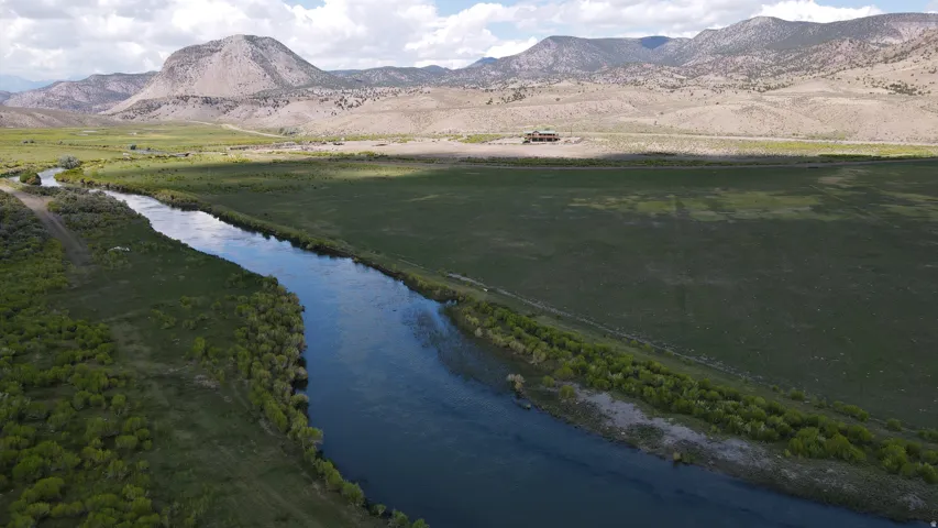 Expansive property featuring a river, verdant fields, rolling hills, and distant mountain ranges