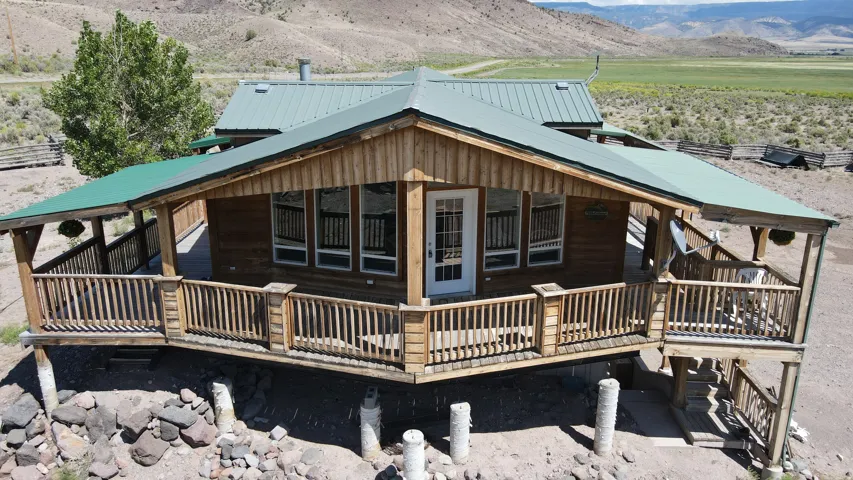 Wood-sided structure featuring a green metal roof and an expansive wrap-around porch