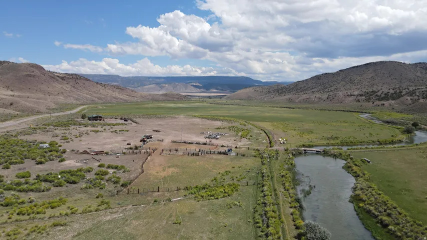Expansive rural property featuring a river, bridge, and surrounding mountainous landscape
