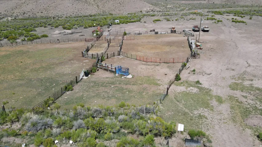 Fenced agricultural land featuring multiple pens, a central corral, and extensive open terrain