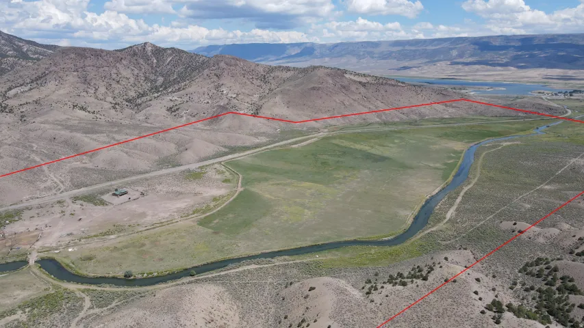 Expansive land parcel featuring a winding river, verdant fields, and mountainous terrain