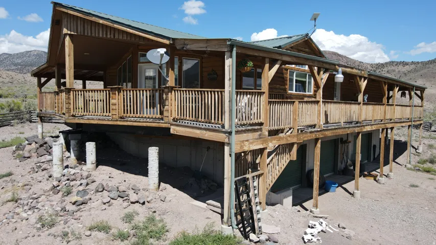 Elevated log-style residence featuring an extensive wooden deck and a metal roof