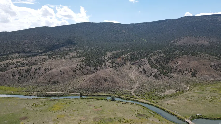 Expansive natural landscape featuring a river, rolling hills, and distant mountains