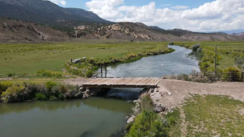 Expansive natural landscape with a winding river and a rustic wooden bridge