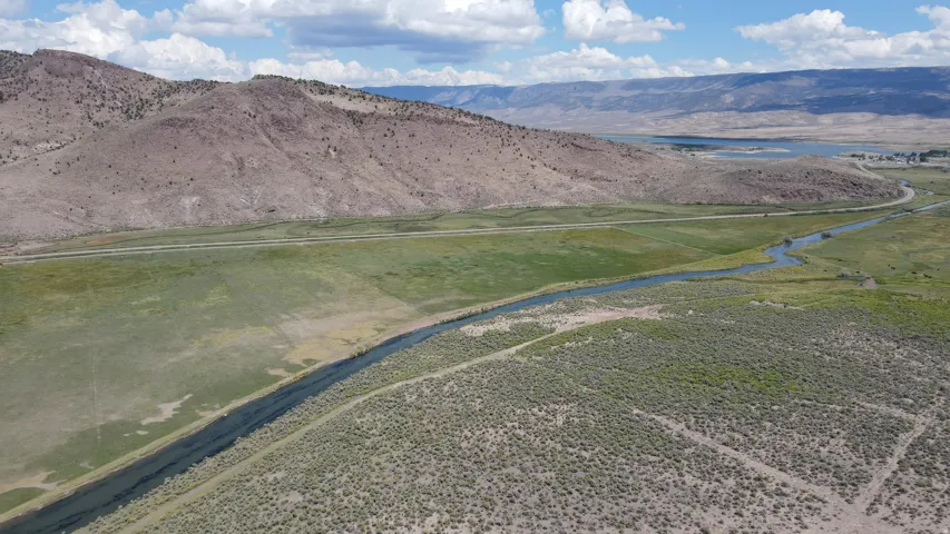 Expansive land featuring a winding river, verdant grasslands, and distant mountains