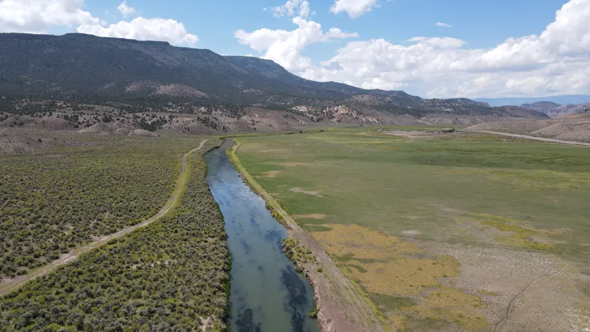 Expansive rural acreage featuring a meandering river and diverse topography, including a large grassy field and shrubland