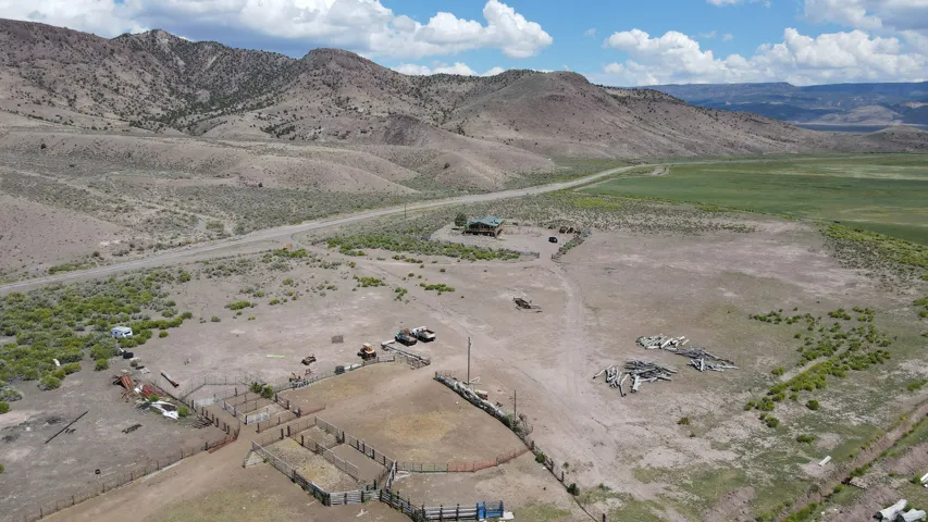 Expansive rural property featuring a main residence, multiple fenced enclosures, and a winding unpaved road