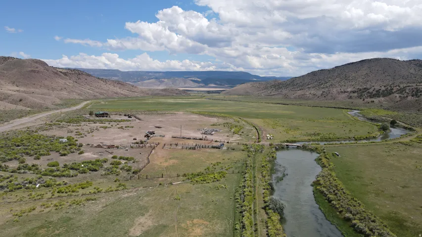 Expansive rural landscape featuring a winding river, verdant fields, and distant hills