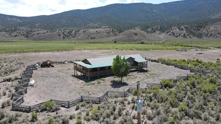 Log cabin style home with a green metal roof and an expansive wrap-around porch