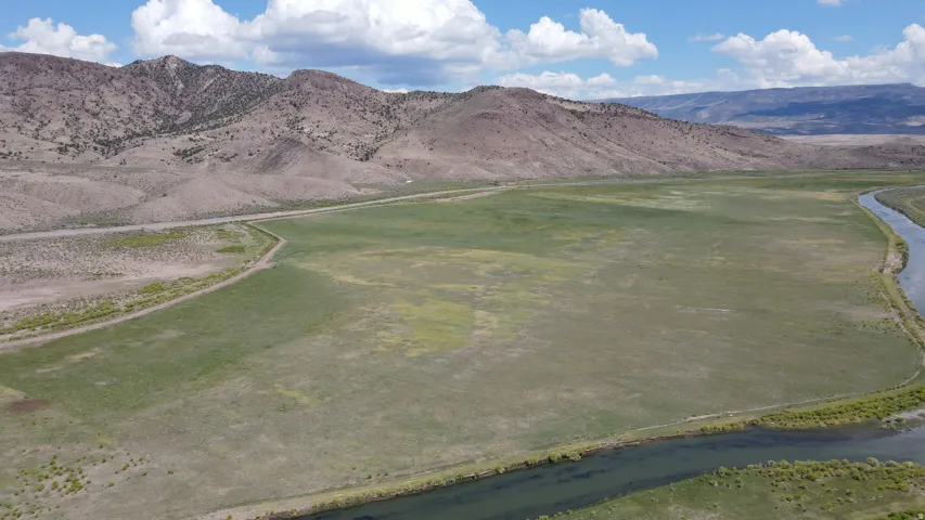 Expansive land parcel featuring open fields, a winding river, and distant mountains