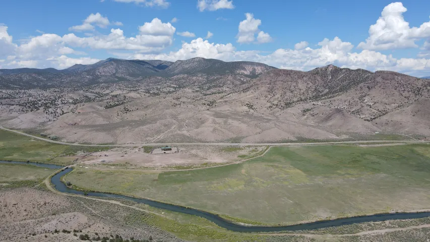 Expansive rural landscape featuring a winding river, verdant fields, and distant mountainous terrain