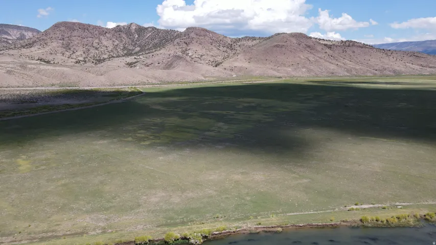 Expansive land parcel featuring open grasslands and a natural water boundary