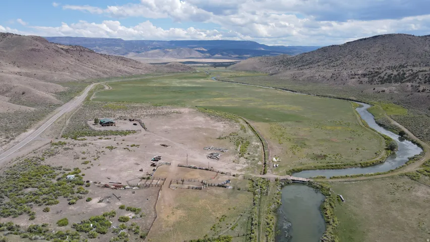 Expansive rural landscape featuring a winding river, green fields, and distant mountainous terrain