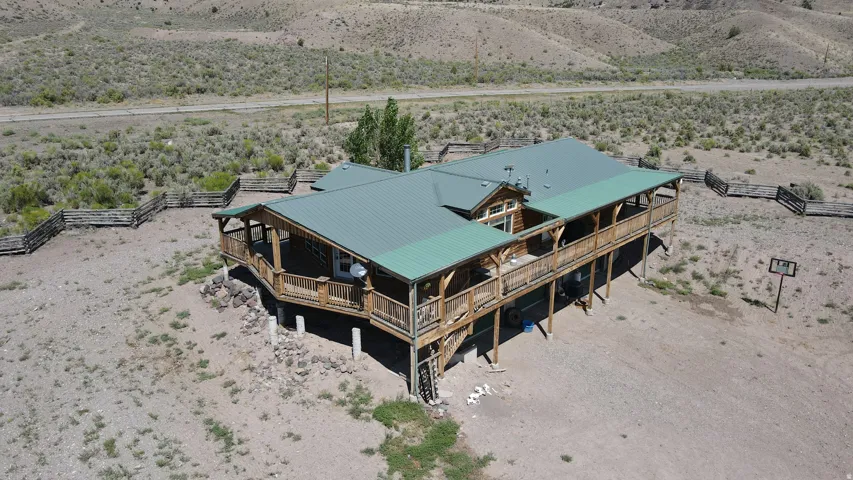 Wood-sided residence featuring an elevated wraparound porch with a wood railing, supported by concrete pillars