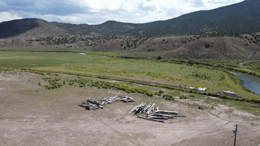 Expansive land parcel featuring a river, verdant fields, and mountainous terrain