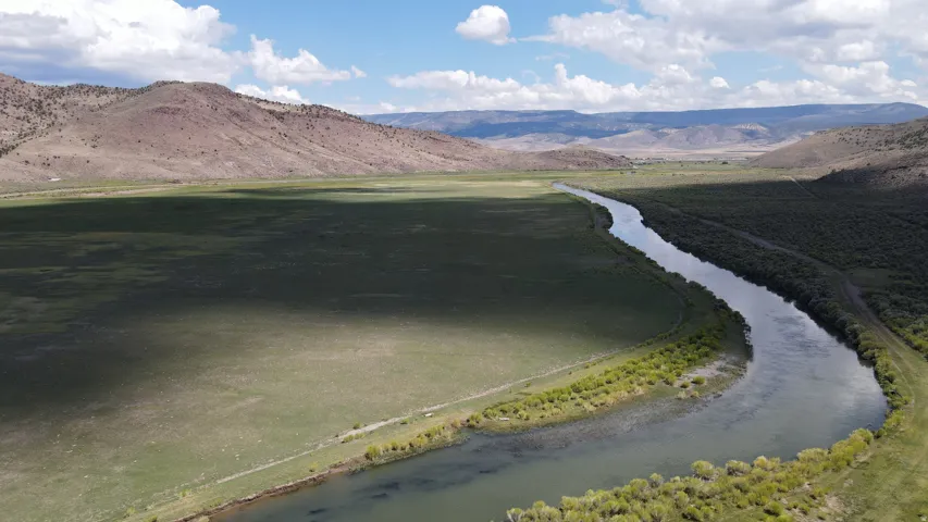 Expansive natural landscape featuring a meandering river and surrounding green plains