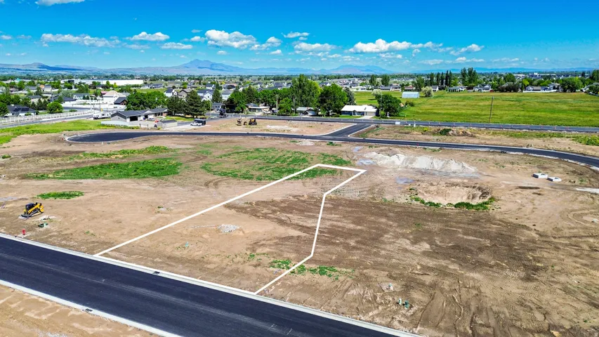 Developed land parcel with established road frontage, surrounding residential structures, and distant mountain range
