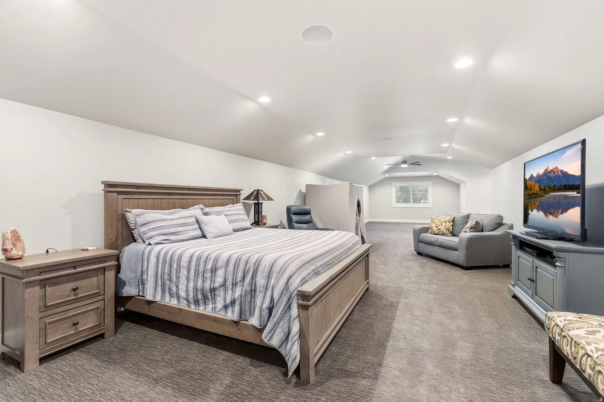 Spacious room featuring vaulted ceilings, recessed lighting, and soft gray carpeting