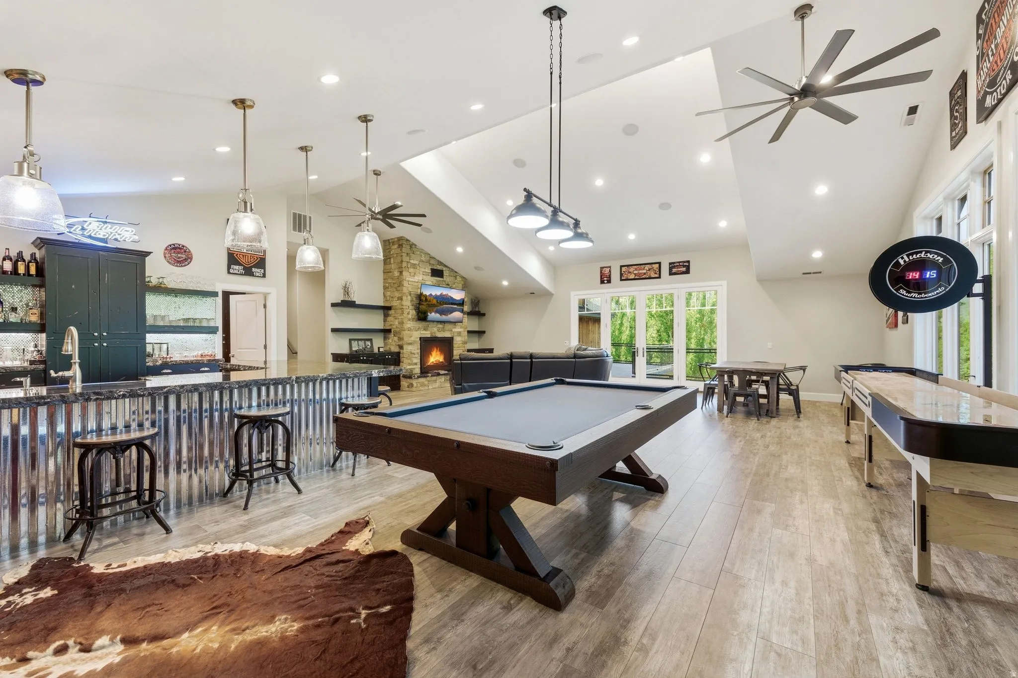 Expansive entertainment space featuring wood-finish flooring and a vaulted ceiling with multiple ceiling fans