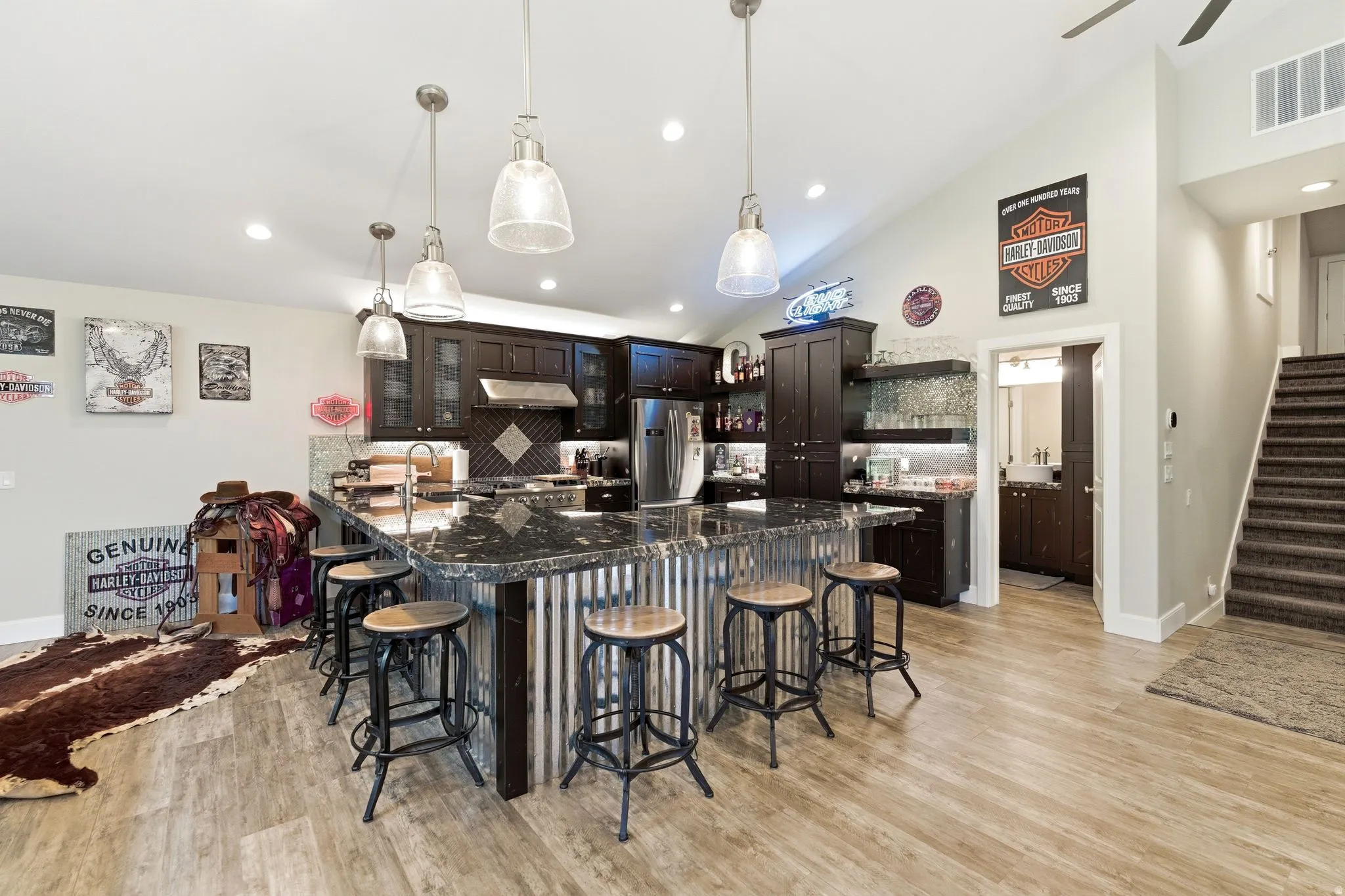 Spacious kitchen featuring an oversized island with a dark granite countertop, dark wood cabinetry, stainless steel appliances, and wood-finish flooring