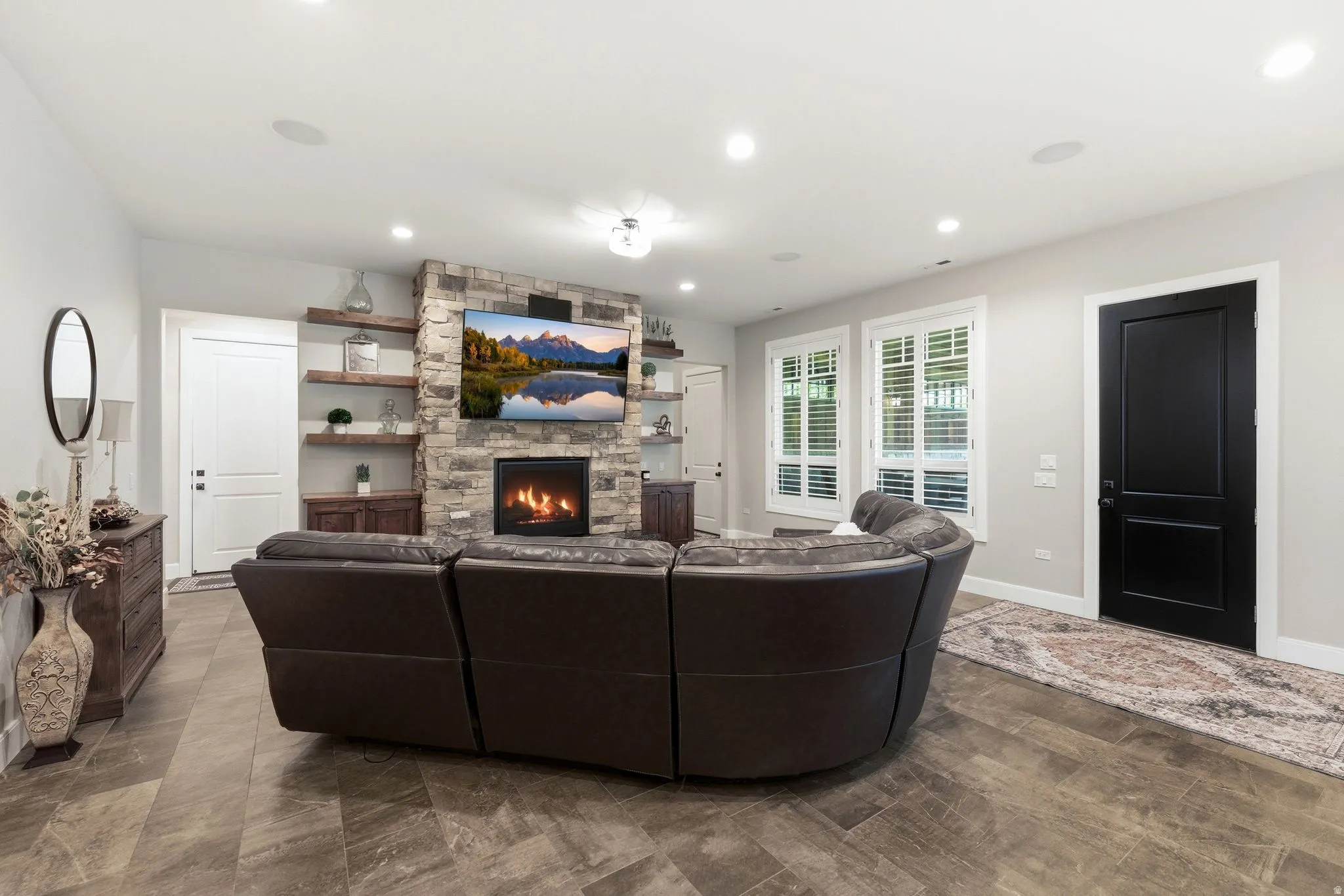 Spacious living area featuring a floor-to-ceiling stone fireplace with an integrated television niche and a gas insert
