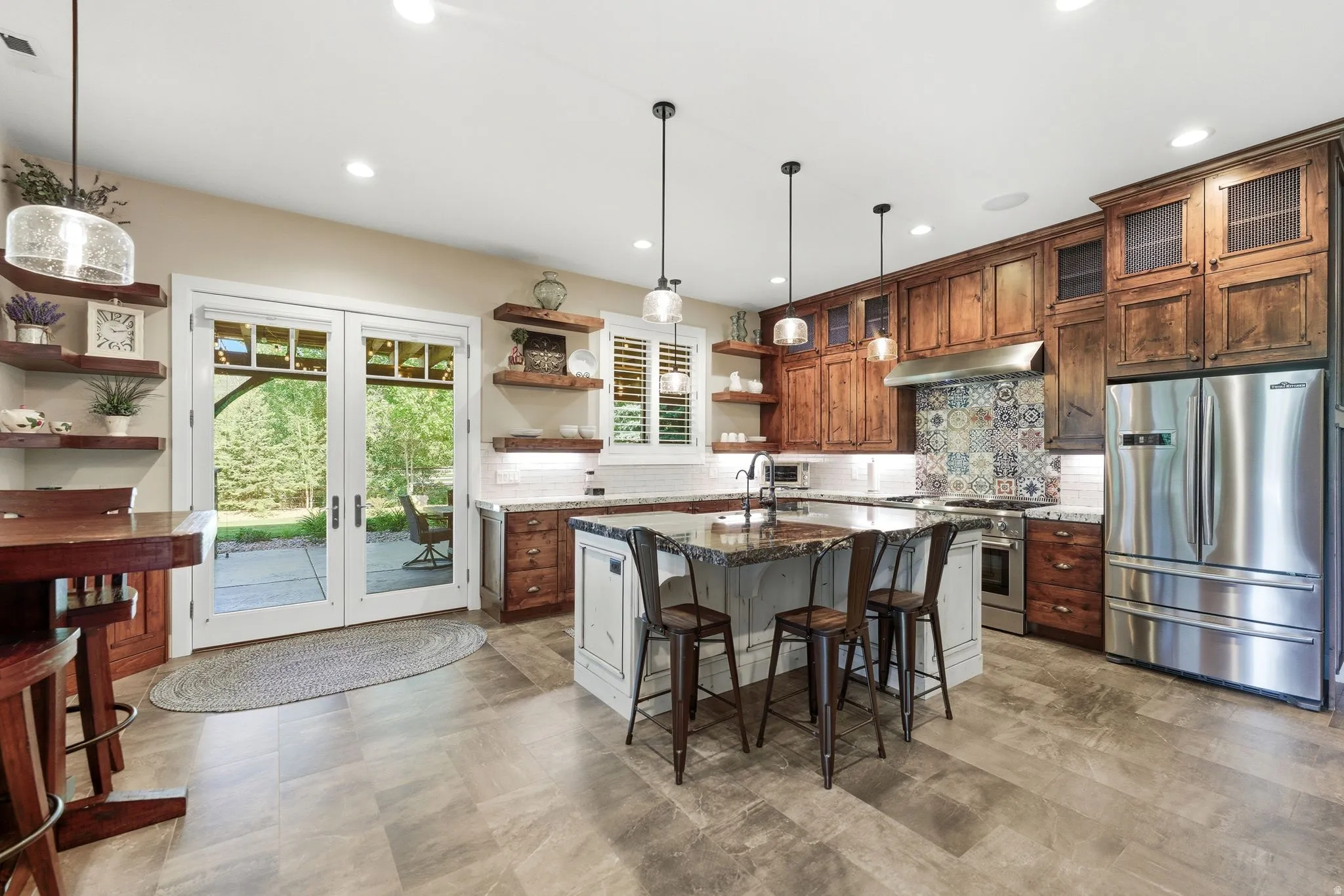 Gourmet kitchen featuring a large central island with seating, stainless steel appliances, custom cabinetry, and a tile backsplash