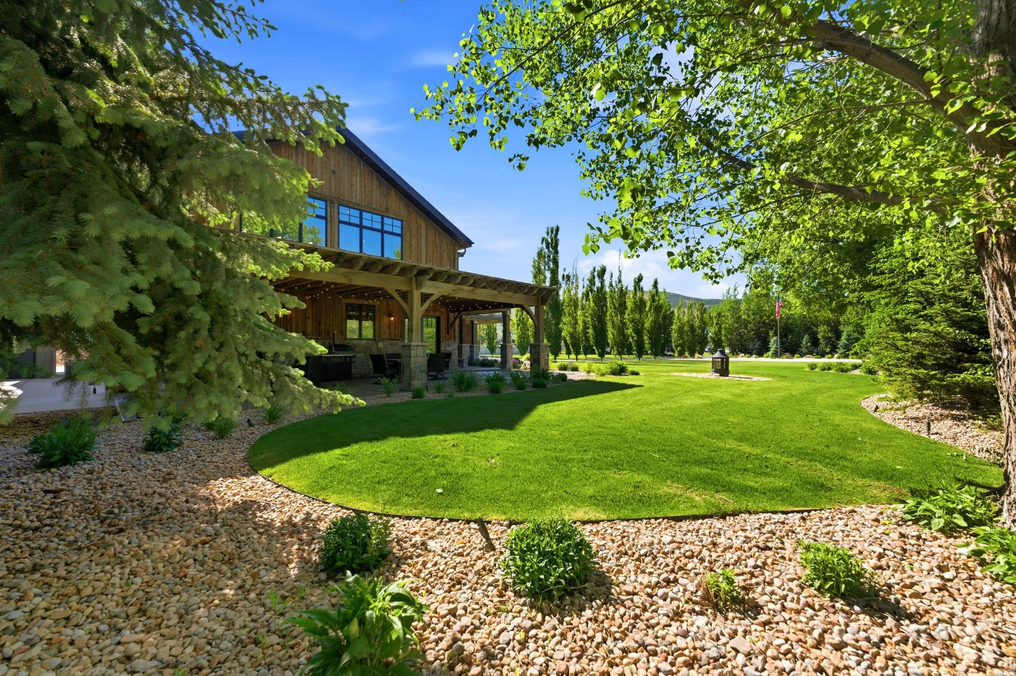 Expansive outdoor space featuring a manicured lawn, gravel landscaping, and mature trees