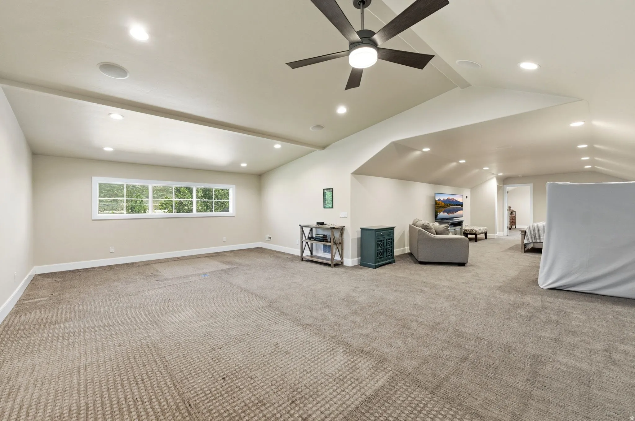 Spacious room featuring neutral carpeting, a multi-pane window, recessed lighting, and a ceiling fan with integrated light