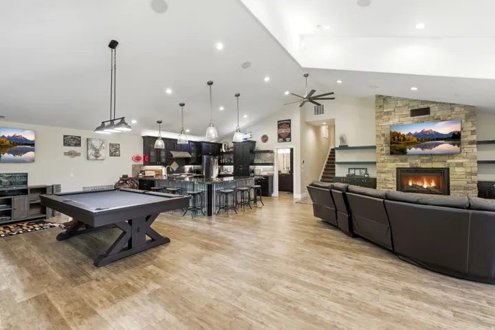 Expansive open-concept room featuring wood-finish flooring, a vaulted ceiling, and recessed lighting