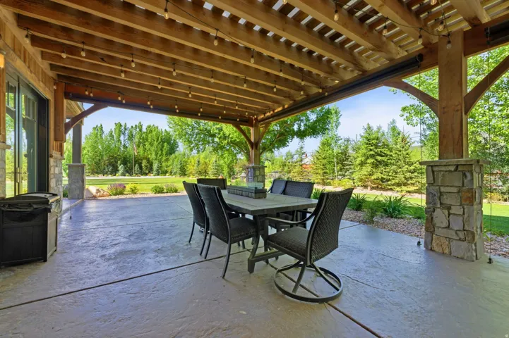 Expansive stamped concrete patio featuring a wood pergola with string lighting