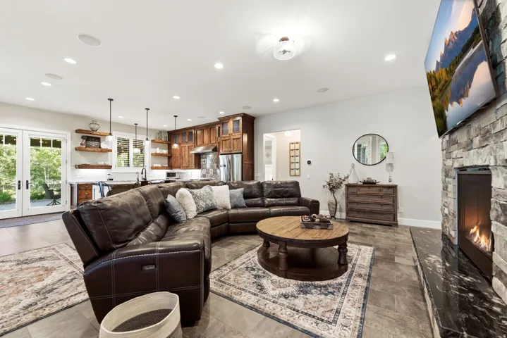 Spacious interior featuring a stone fireplace with a black stone hearth, recessed ceiling lighting, and tile flooring