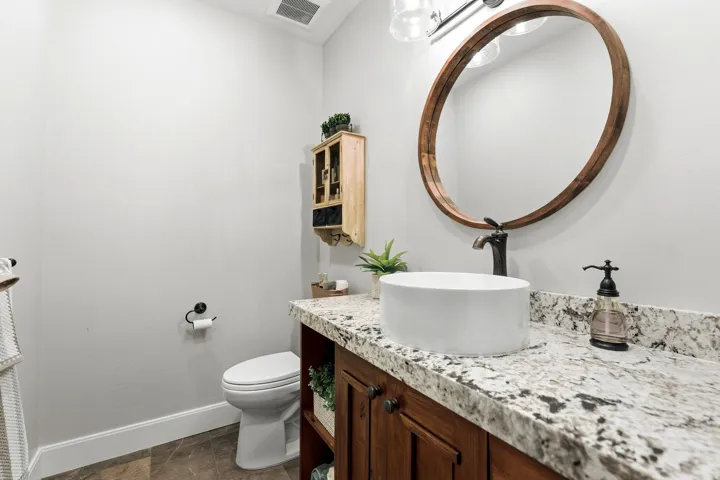 Bathroom featuring a white vessel sink, a dark wood-framed mirror, and a speckled countertop