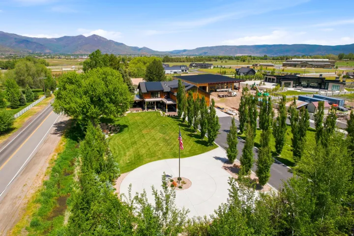 Expansive property featuring a circular driveway, mature landscaping, and mountain backdrop