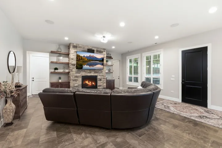 Spacious living area featuring a floor-to-ceiling stone fireplace with an integrated television niche and a gas insert