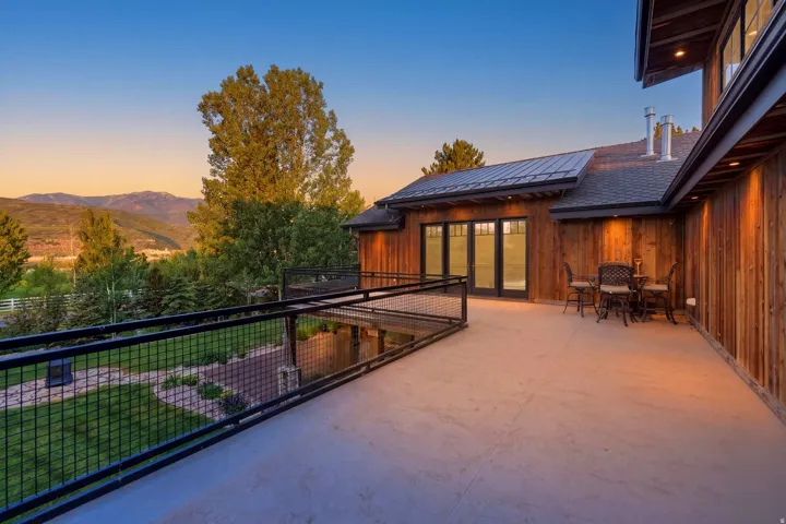 Spacious outdoor patio featuring a concrete surface, black metal railing, and cedar plank siding