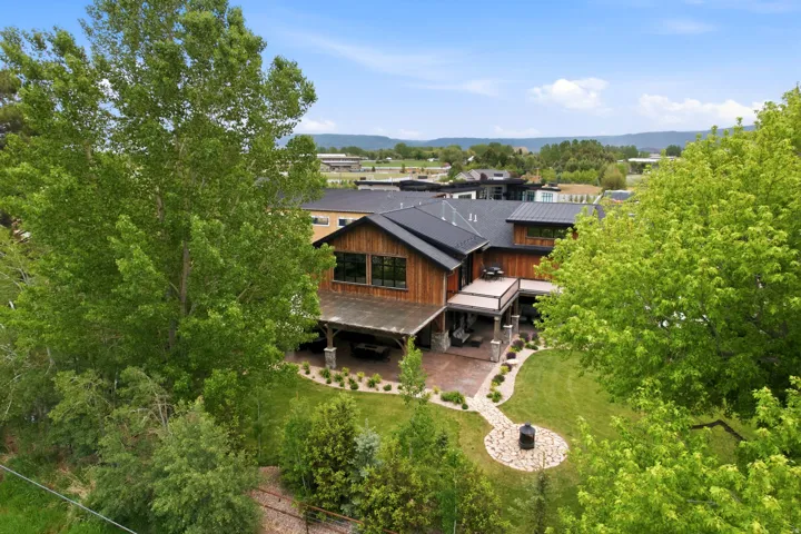 Modern residence featuring a wood-panel exterior, a dark shingled roof, and multiple large windows