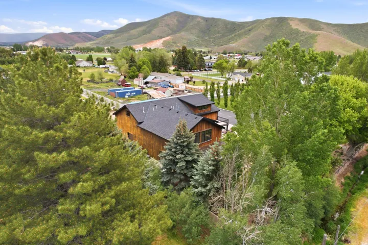 Wood-sided dwelling featuring a multi-pitch roofline, dark shingle roofing, and a prominent second-story balcony