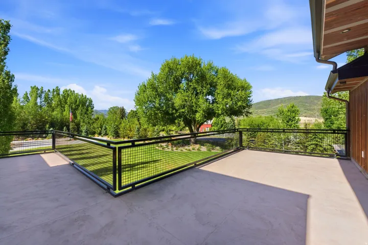Spacious outdoor deck with concrete flooring and dark metal mesh railings