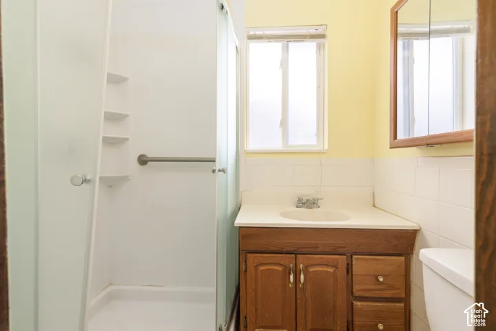 Bathroom featuring a wood vanity with integrated sink, white tile backsplash, and a medicine cabinet with a wood frame