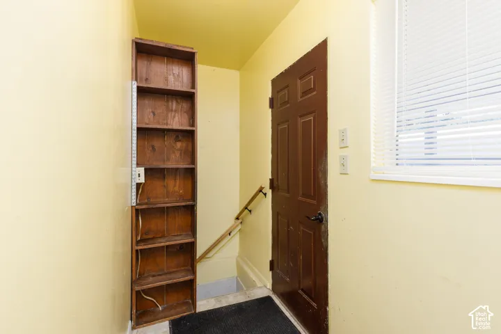 Entryway featuring a wood panel door, natural light from a window with blinds, and built-in wood shelving