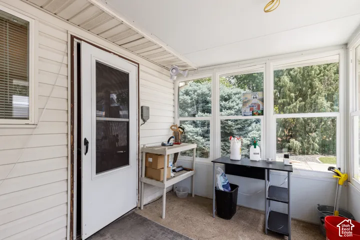 Enclosed porch featuring multiple windows, vinyl siding exterior, and a white screen door