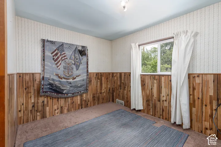 Room featuring wood paneling, wall-to-wall carpeting, and a window with natural light