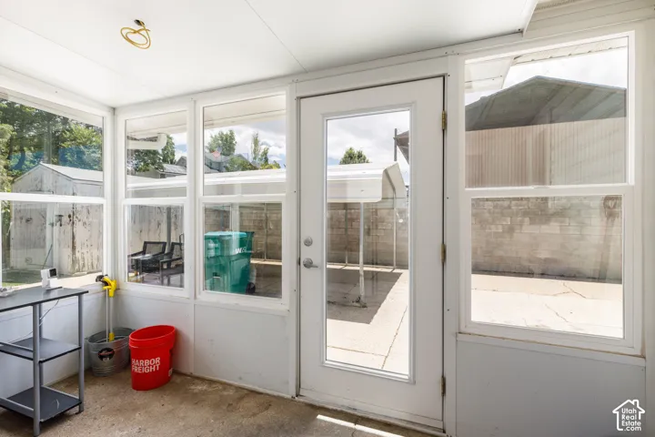 Enclosed sunroom with multiple large windows, a full-lite exterior door, and a textured concrete floor